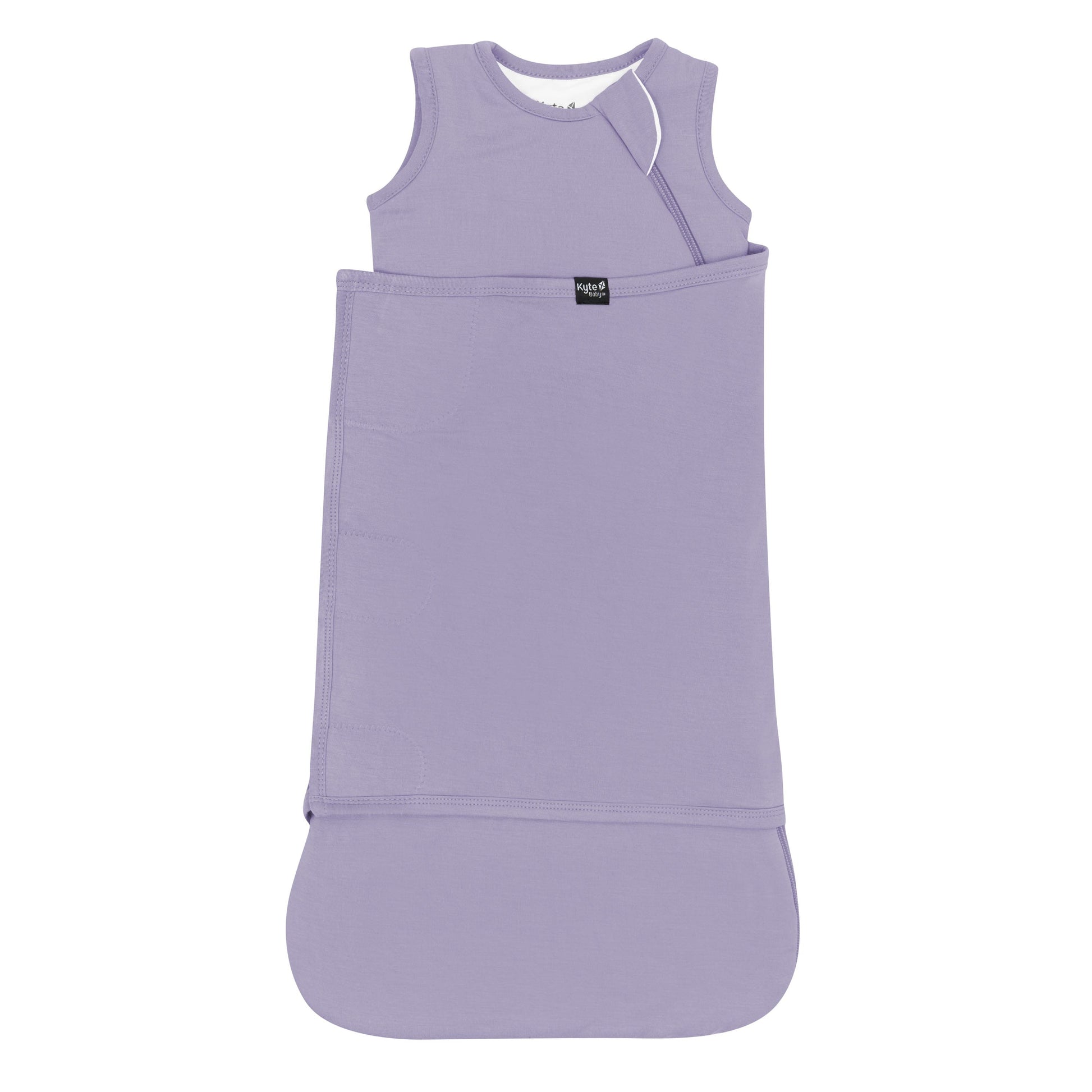 Sleep Bag Swaddler in Taro 1.0 shown swaddled with the black Kyte Baby logo tag visible