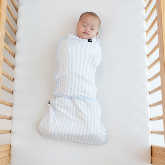 Sleeping Baby laying in a crib swaddled in the Sleep Bag Swaddler in Small Mist Stripe 1.0