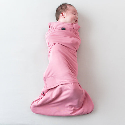 Newborn swaddled in Kyte Baby Sleep Bag Swaddler in Apple Blossom with elastic band