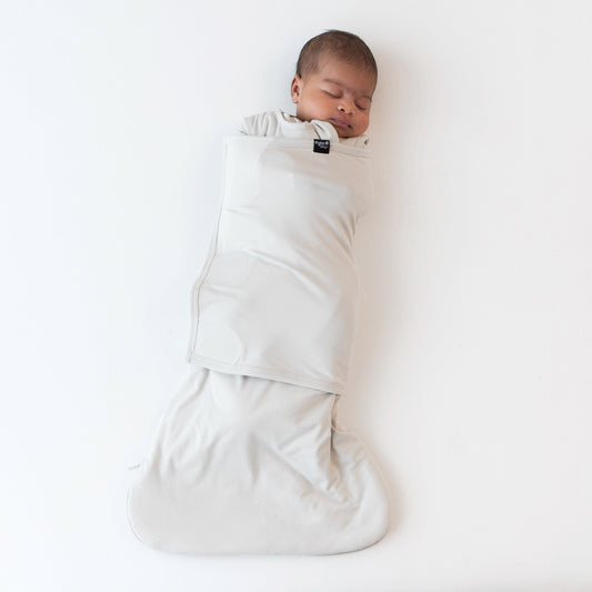 Sleeping baby swaddled in the Sleep Bag Swaddler in Oat 1.0