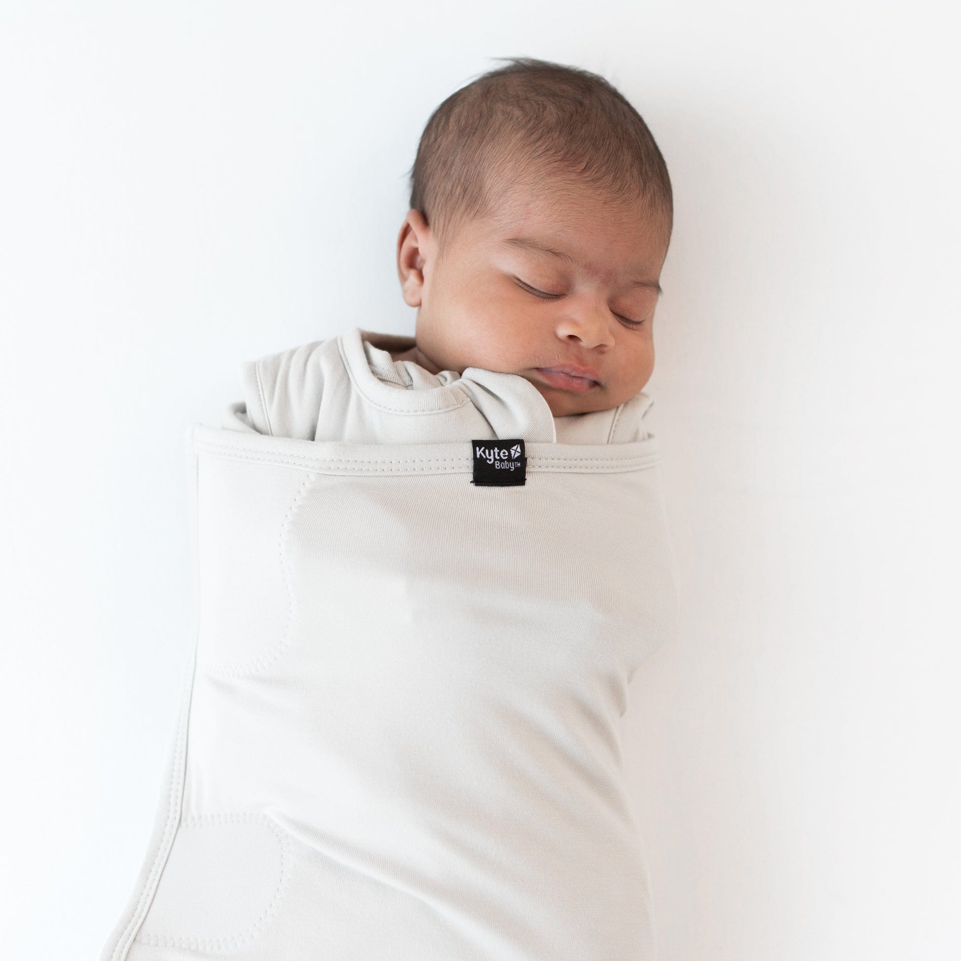 Close up of sleeping baby swaddled in the Sleep Bag Swaddler in Oat 1.0